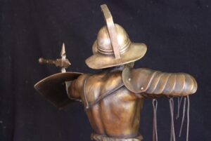 Murmillo Gladiator Bronze Statue, dynamic bronze sculpture of the Murmillo type of gladiator carrying shield, sword and wearing a heavy helmet. Fighting stance with ax embedded into the shield.