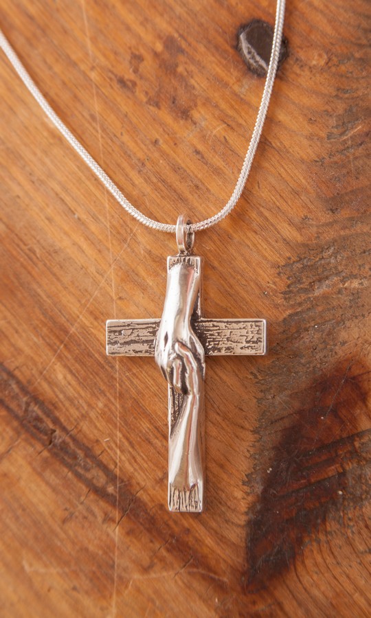 Tom White Studios, Inc | Cross Sculptures Rescued Cross silver necklace created by Christian sculptor, Tom White. Depicts Jesus nail-scarred hand rescuing mankind by His great love shown on Calvary by His death and the power of His Resurrection. Available in necklaces and bronze wall hangings.