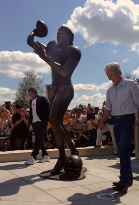 Statue unveiling with crowd and clear sky.